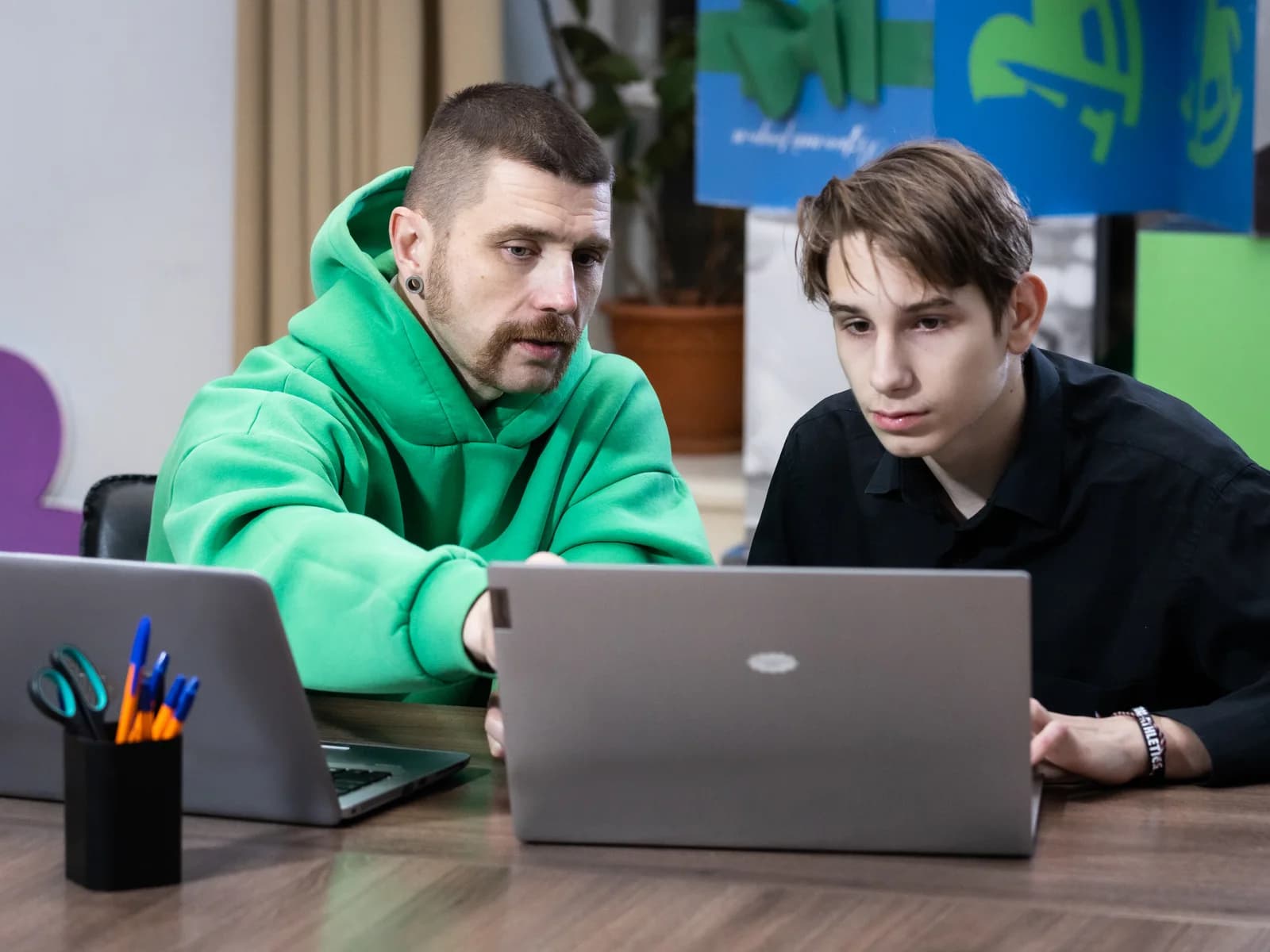 Совершеннолетний наставник и подросток вместе работают над заданием